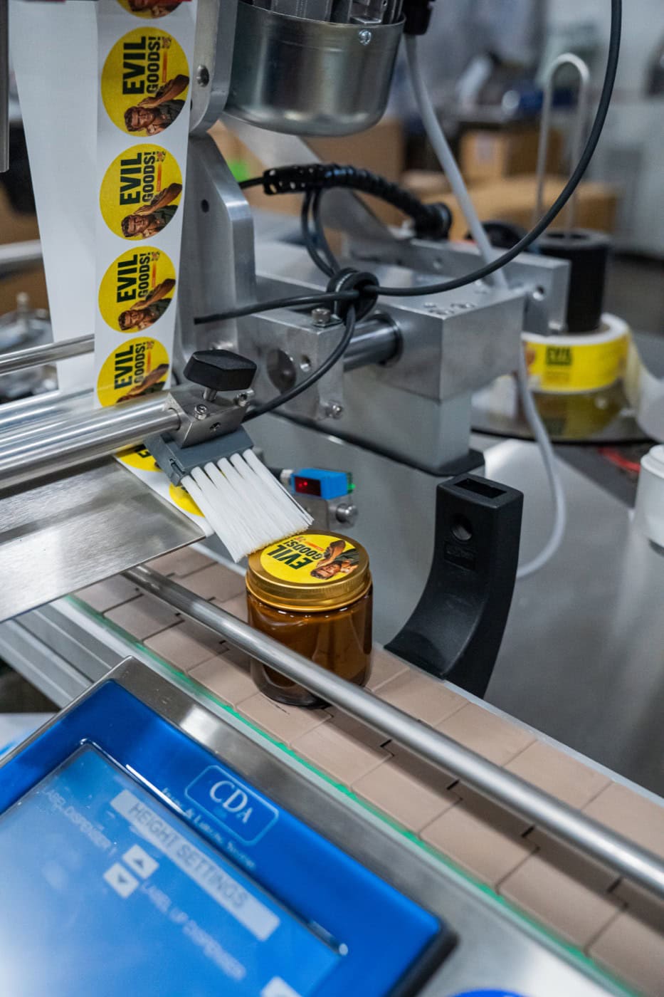 Automated labelling machine applying printed labels to an amber glass jar on the conveyor at the Moe’s Group facility in Chatsworth, California